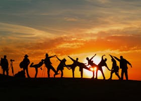 Group of people silhouetted against a vibrant sunset, showcasing unity and joy.